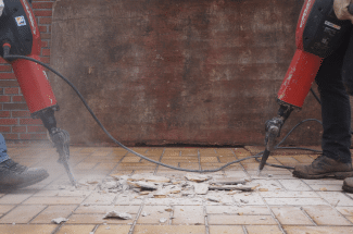 Two workers are using drills to demolish tiles